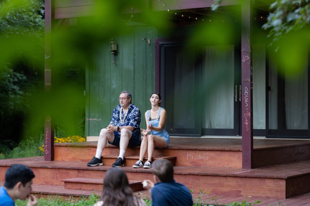 Kate performs with an audience member. They are sitting on the stage.