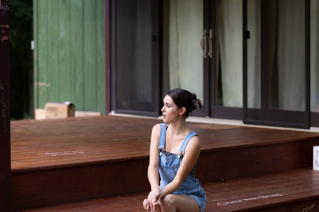 Katie sits on the stage, talking to the audience