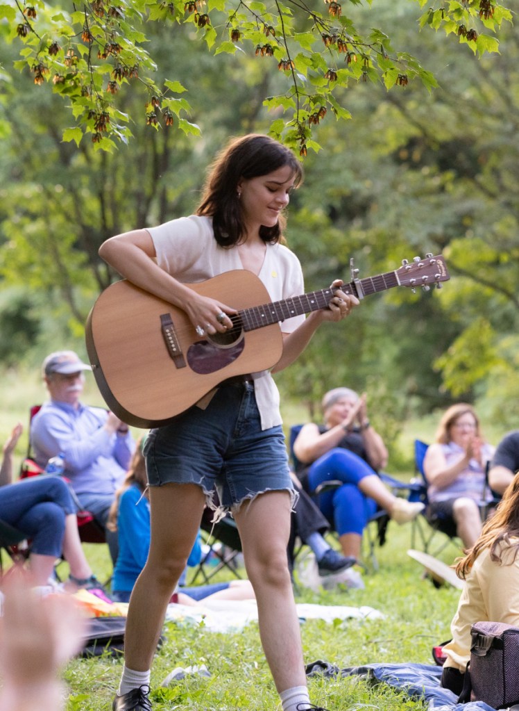 Azalea walks through the crowd playing the guitar.